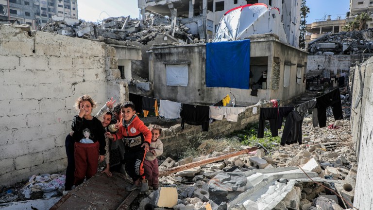 A group of children standing on rubble in Gaza.