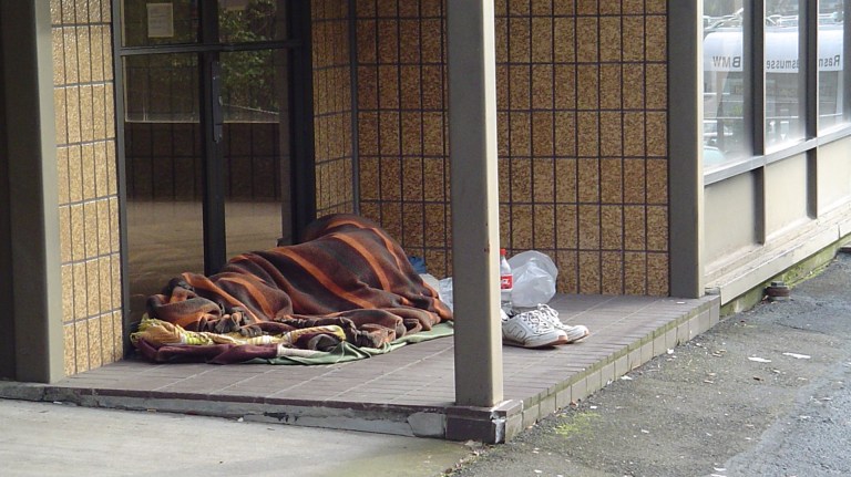 a homeless person sleeping rough in a doorway