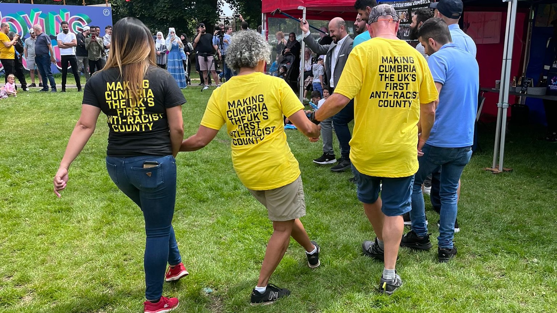 Anti Racist Cumbria - three people holding hands and skipping