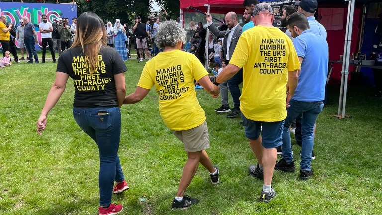 Anti Racist Cumbria - three people holding hands and skipping