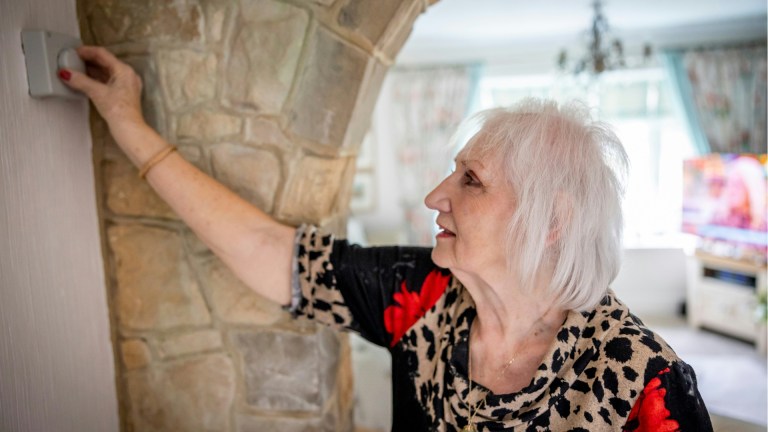 old woman adjusting heating thermostat