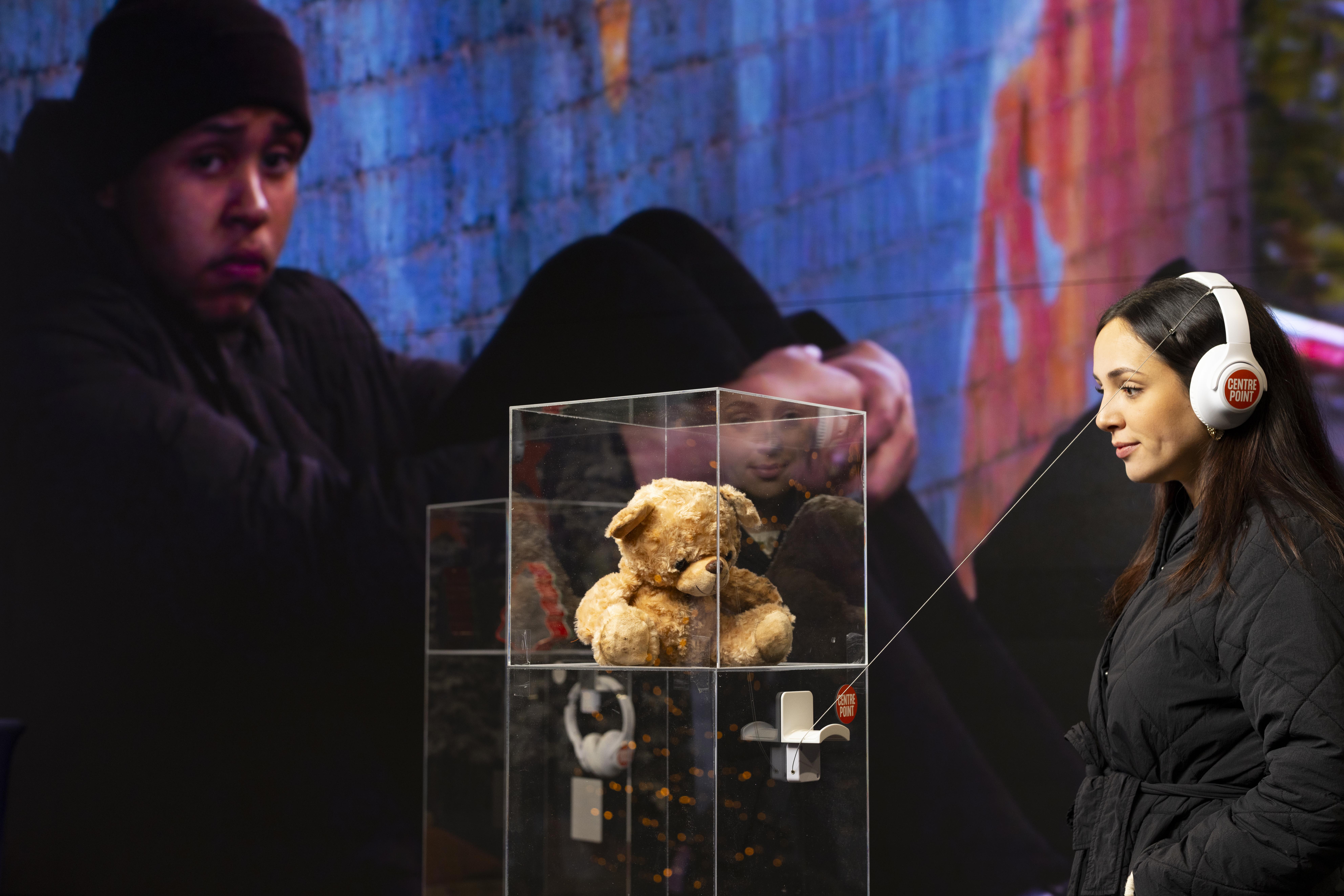 A woman looks at a teddy bear at Centrepoint's installation showcasing "lifeline" objects from young homeless people
