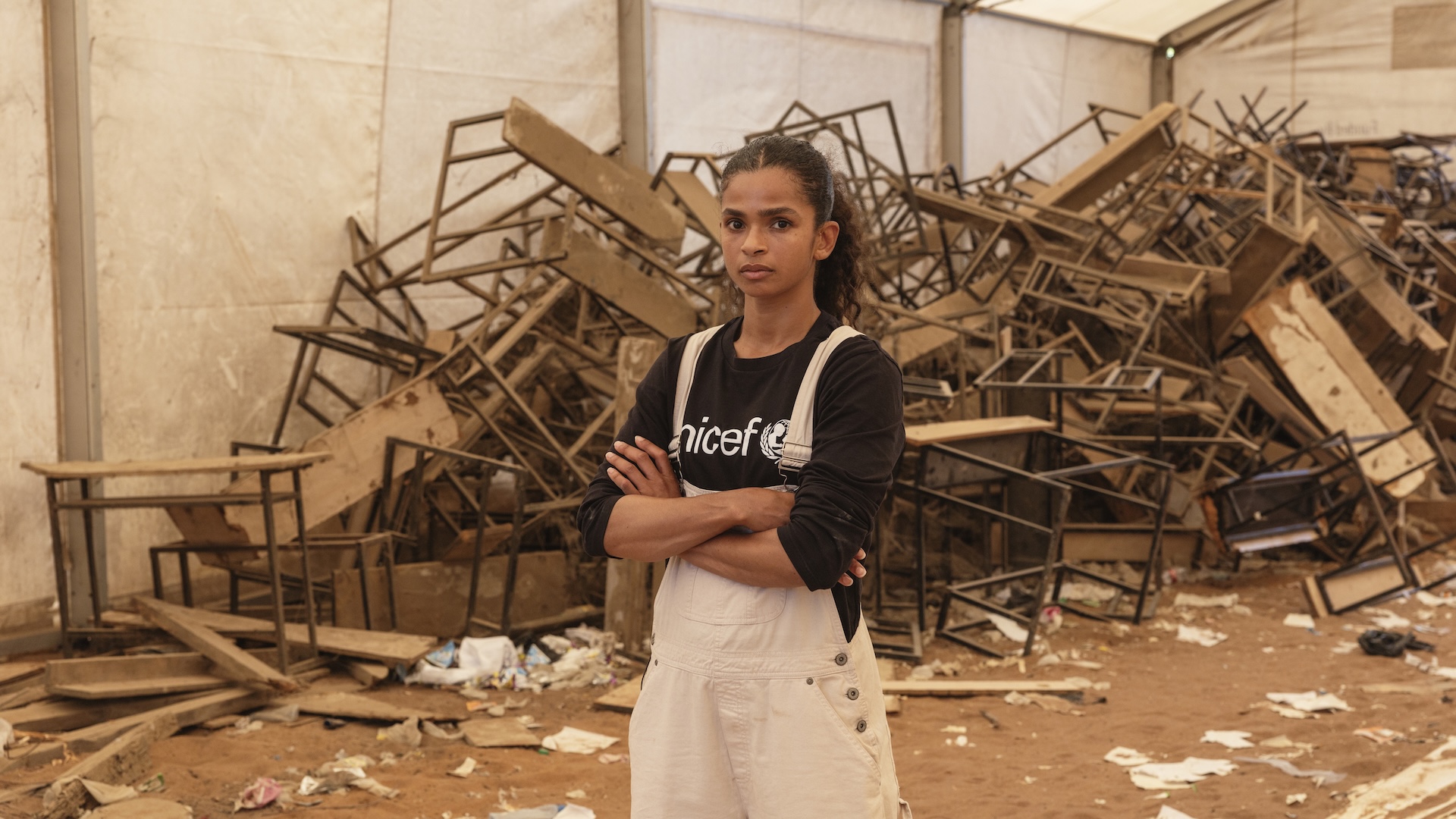 British-Somali boxer Ramla Ali in front of a pile of broken, discarded desks in Dadaab refugee camp.