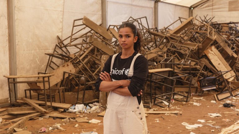 British-Somali boxer Ramla Ali in front of a pile of broken, discarded desks in Dadaab refugee camp.