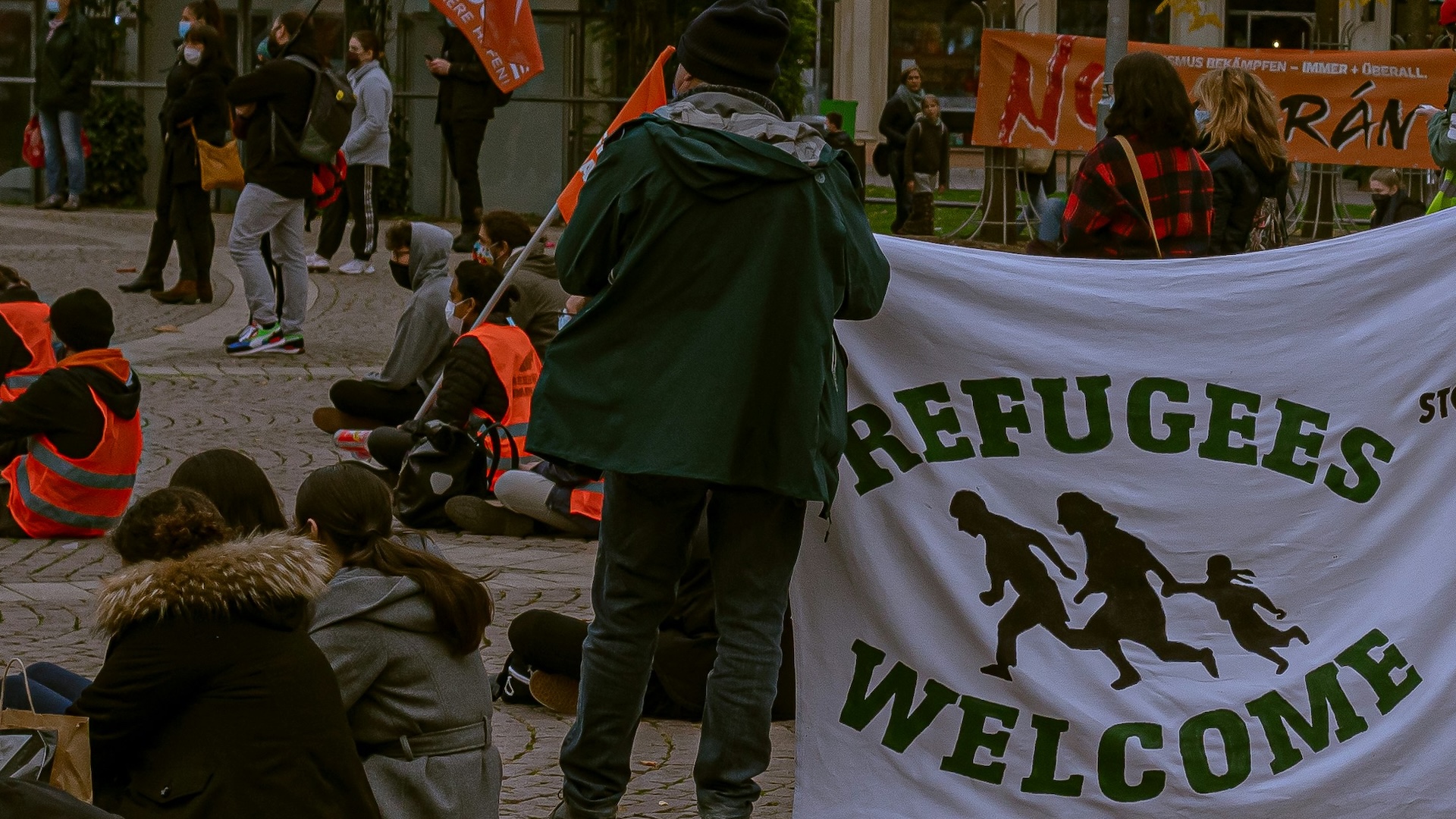 A person holding a banner saying 'Refugees Welcome'.