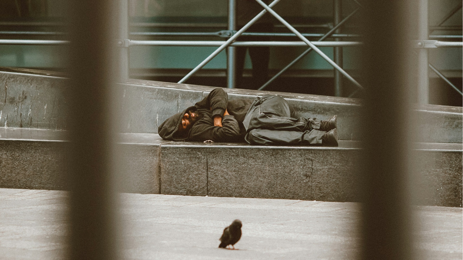 a homeless man lying down sleeping rough on the street