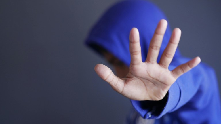 a person dressed in a hoodie holding out their palm