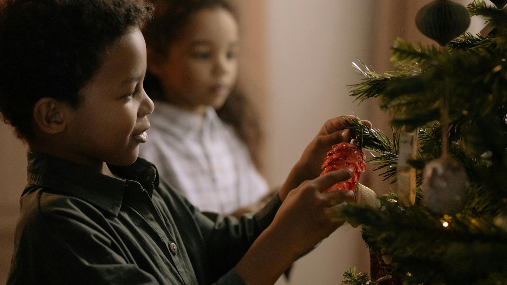 Little boy puts a decoration on a Christmas tree