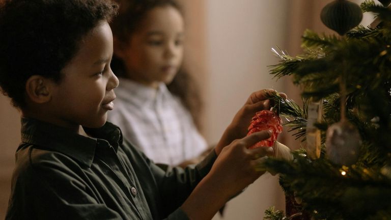 Little boy puts a decoration on a Christmas tree