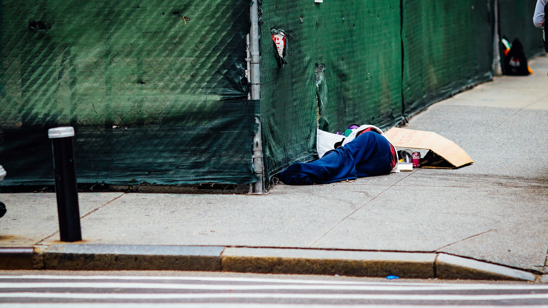 a homeless person lying on the street with their belongings