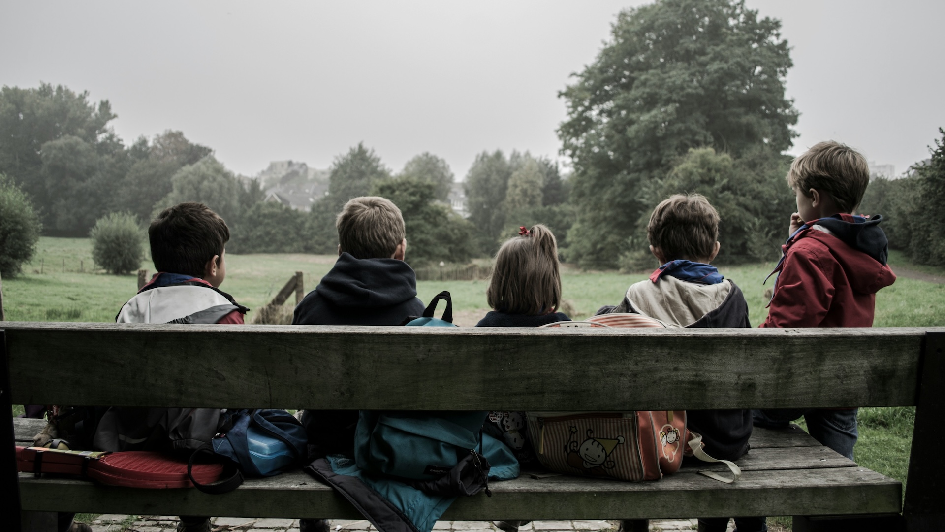 A group of children sitting on a bench together.