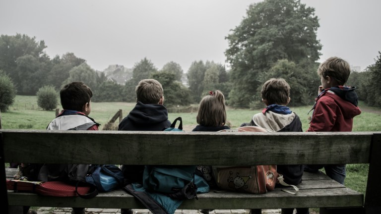 A group of children sitting on a bench together.