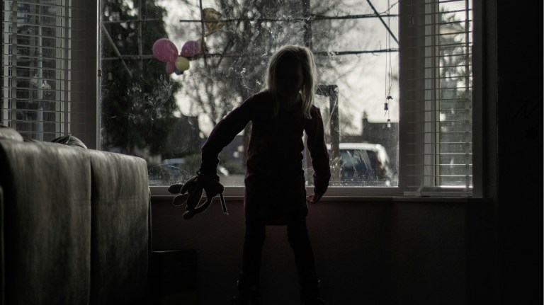 a girl in the front room of a home in front of the window