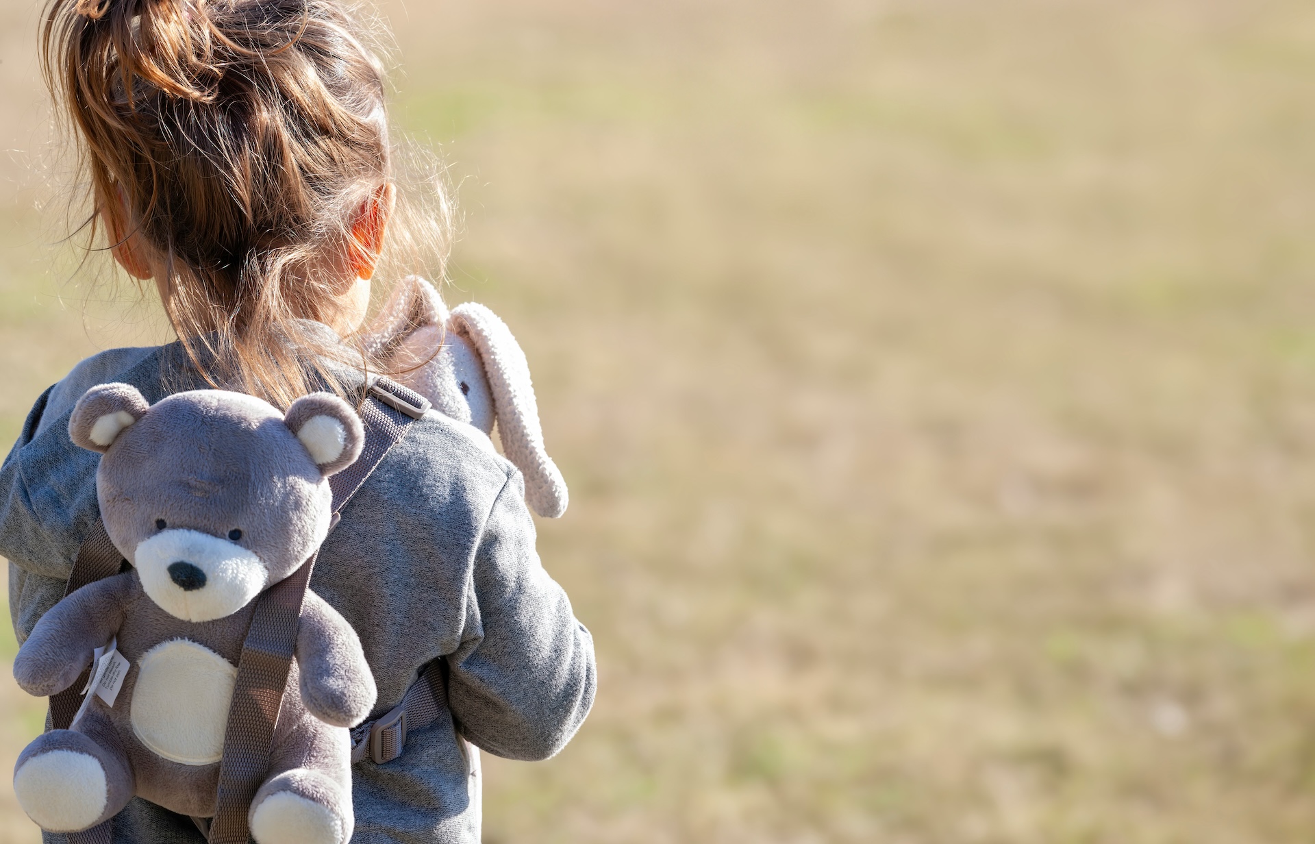 A child wearing a teddy bear backpack
