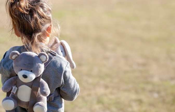 A child wearing a teddy bear backpack