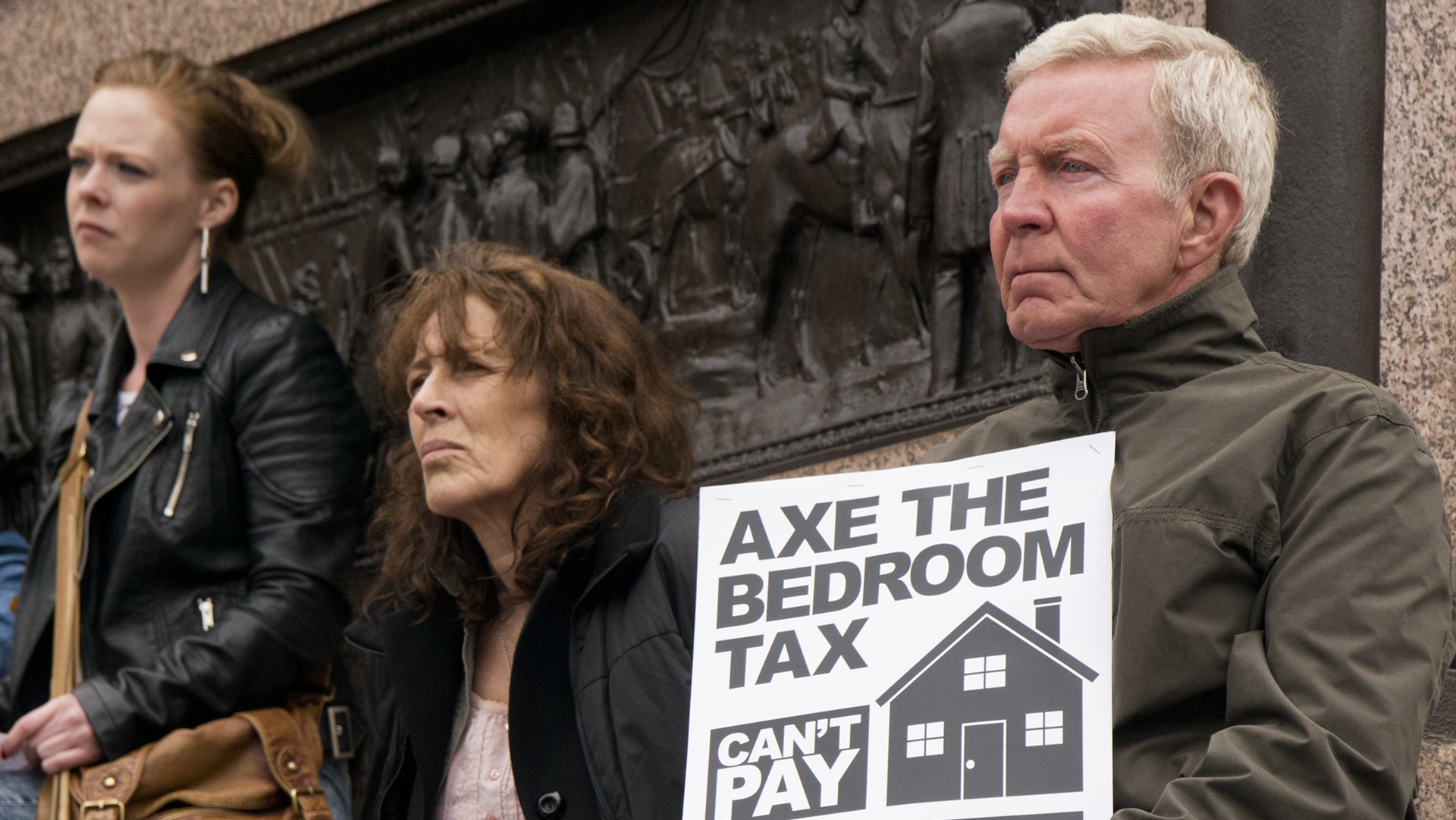 protesters hold up a placard calling for leaders to axe the bedroom tax