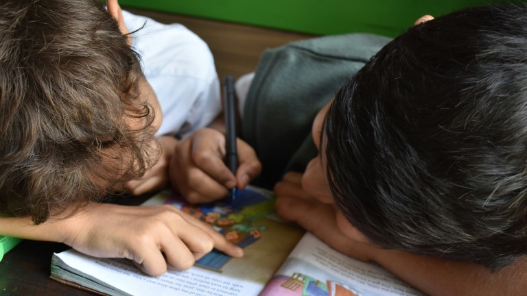 Children together writing on book