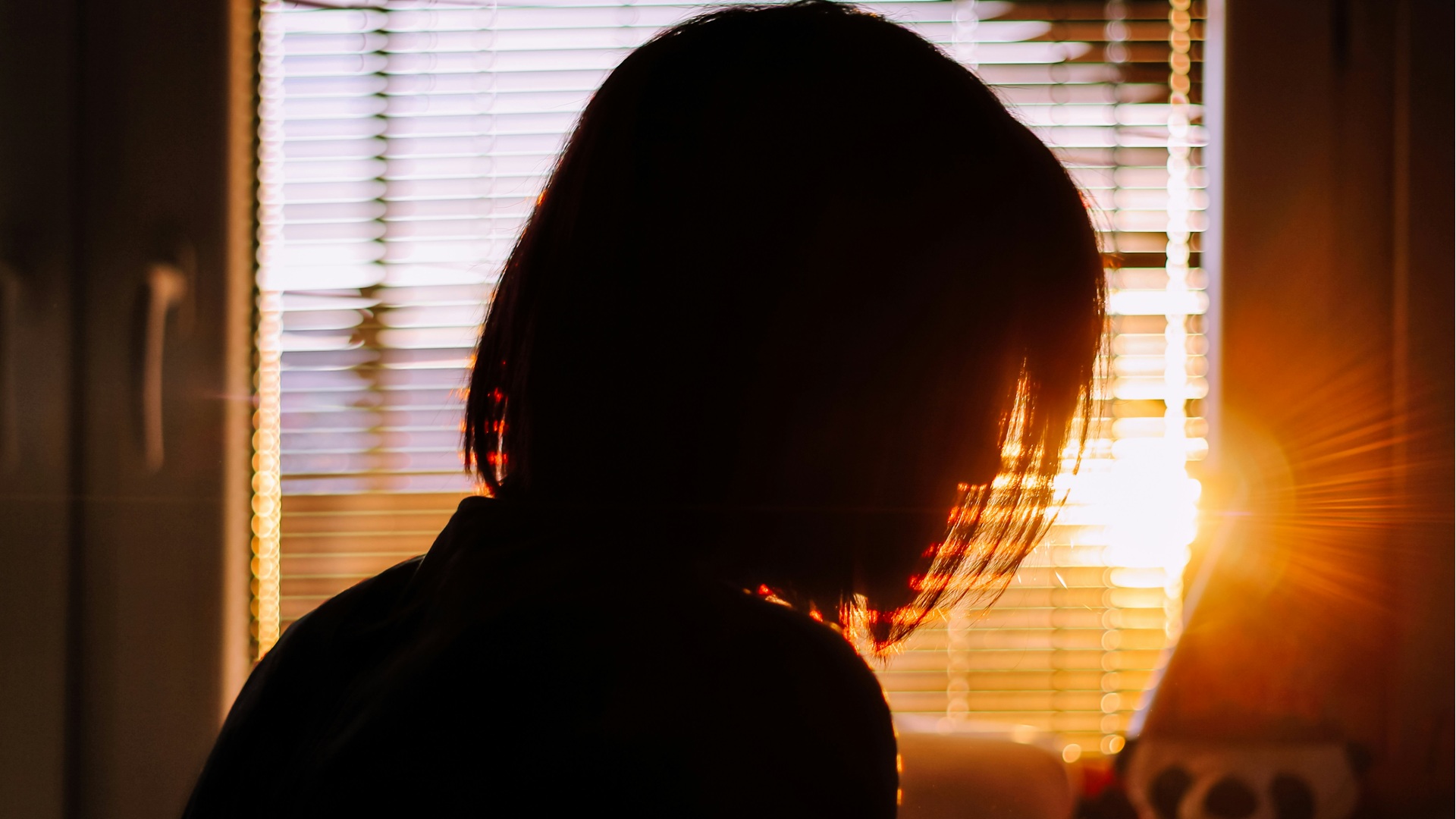the silhouette of a women in a flat in front of the sun