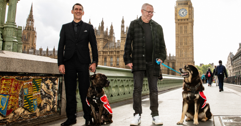 2 vendors stand on westminster bridge with their dogs