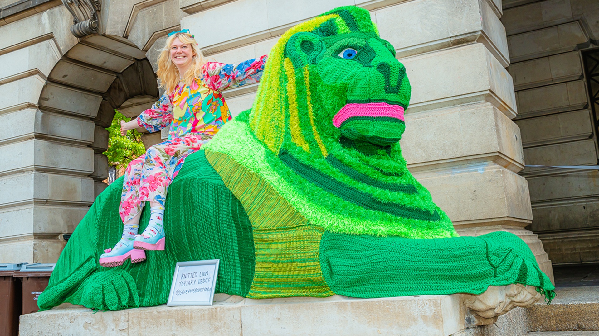 A woman sat on a green knitted lion at Green Hustle Festival