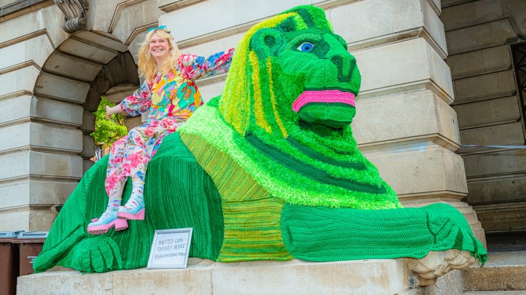 A woman sat on a green knitted lion at Green Hustle Festival