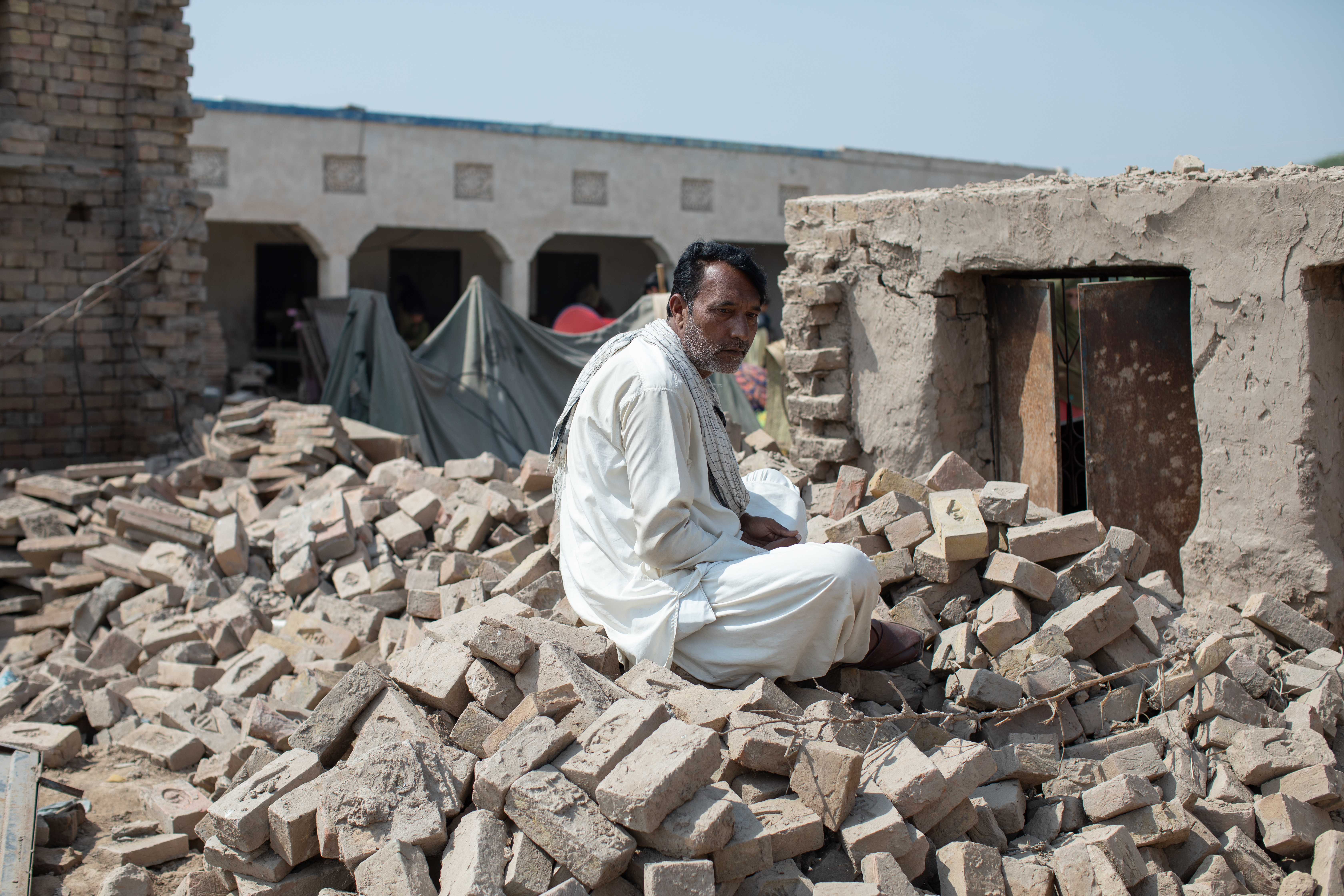 A farmer sits in the rubble of his destroyed property