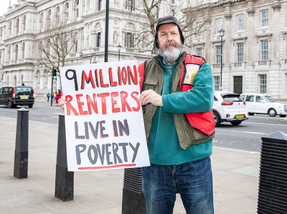 Big Issue vendor John holds a sign reading 9 million renters live in poverty