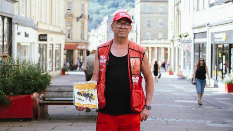 Big Issue vendor Ian Duff stands with a magazine on Union Street in Bath.