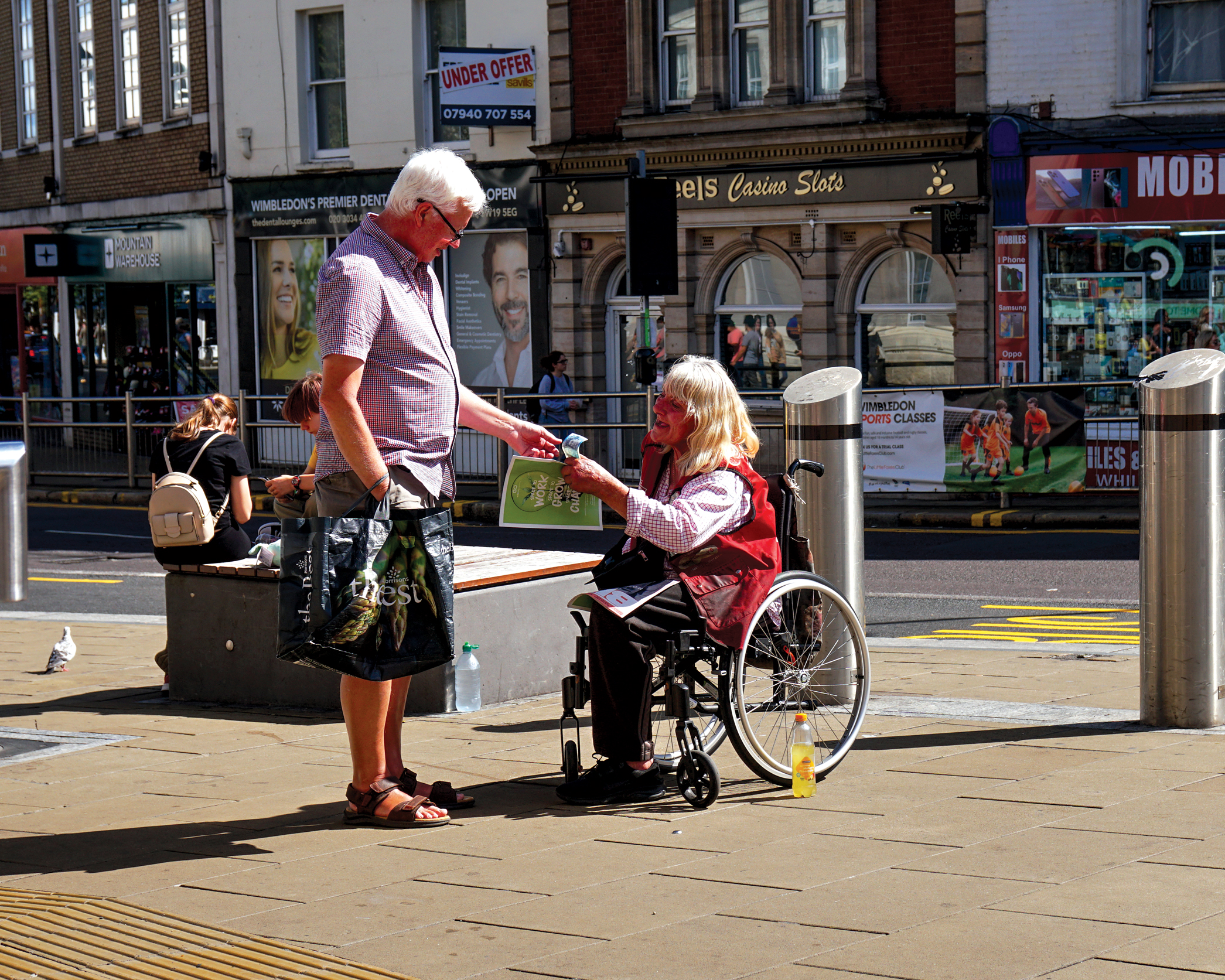 Big Issue vendor Jane Burns selling the magazine to a customer in Wimbledon