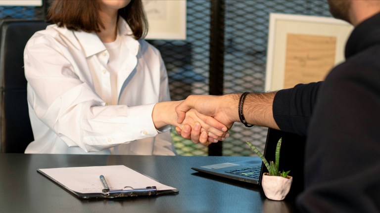 a woman shaking hands with a man at a desk