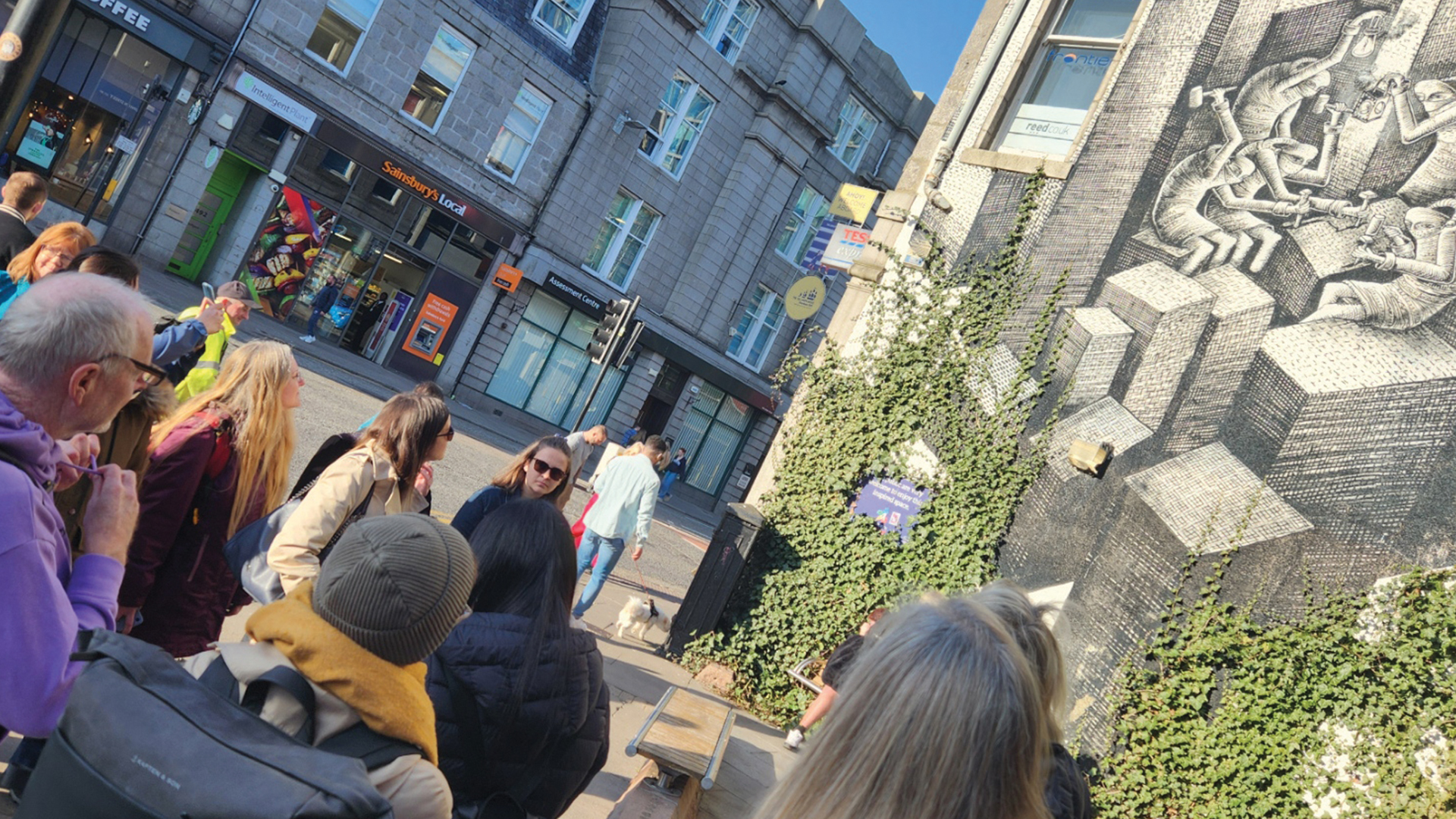 Invisible Cities tour guide showing a tour group a mural by Sheffield artist Phlegm at Holborn Junction, Aberdeen