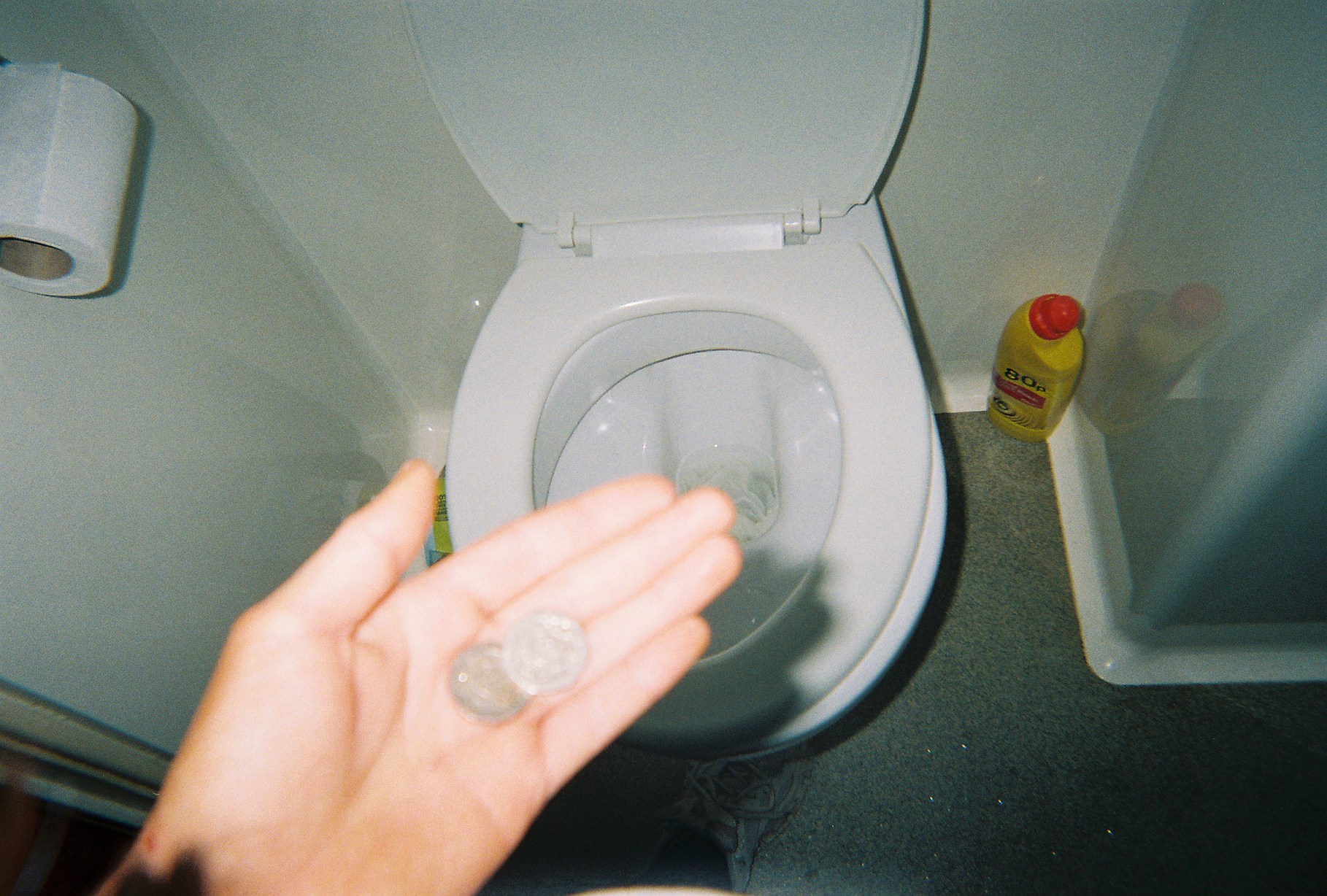 A woman holds out some coins above a toilet to demonstrate the stigma around menstruation and homelessness