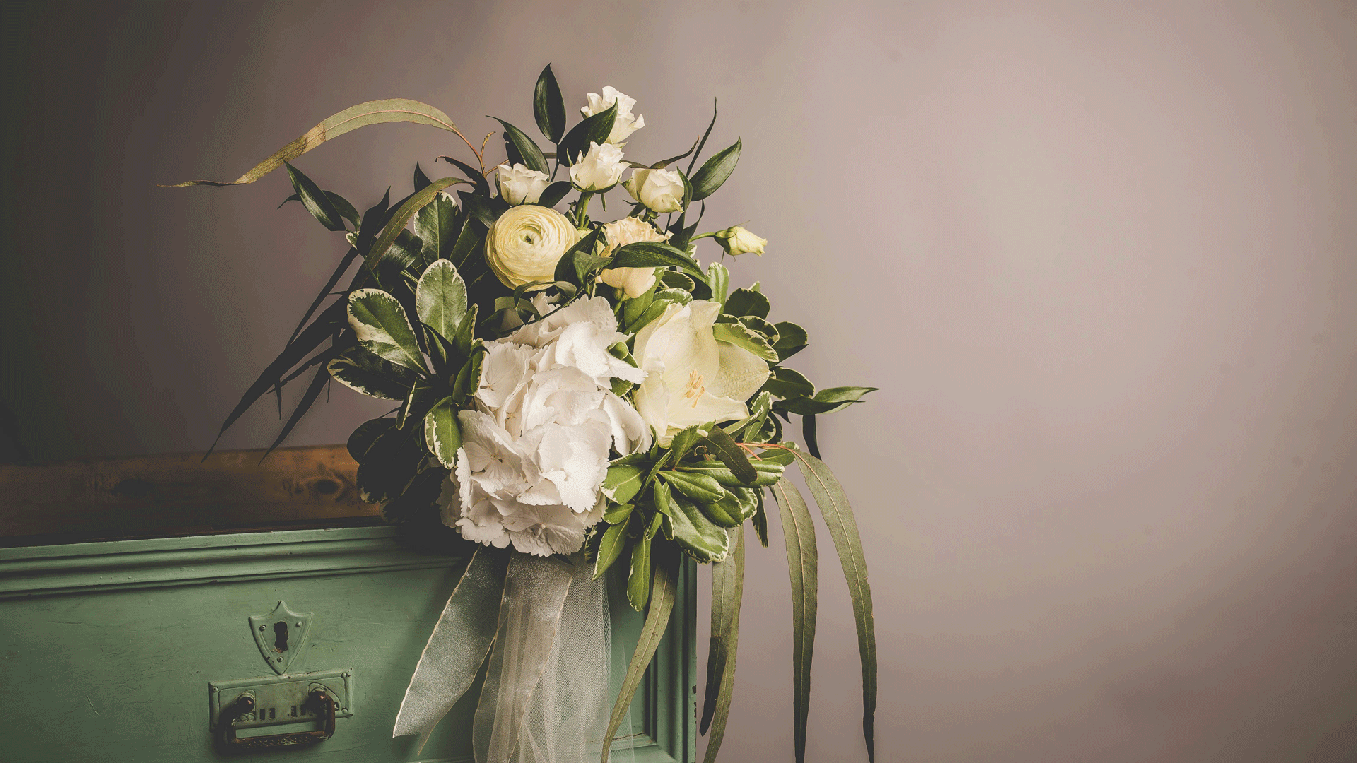 white and yellow flowers in a vase in front of a grey background