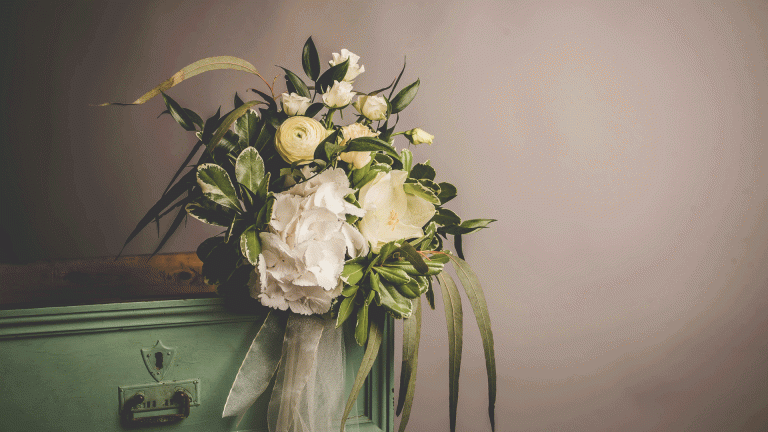 white and yellow flowers in a vase in front of a grey background